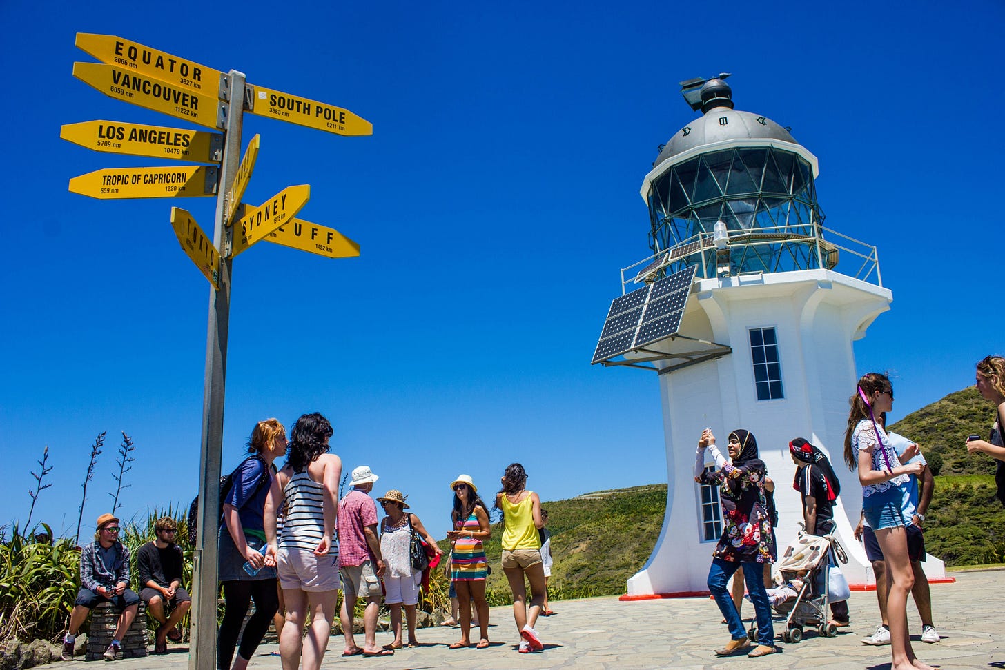 Crowd on a beach by a lighthouse in North Island, New Zealand.