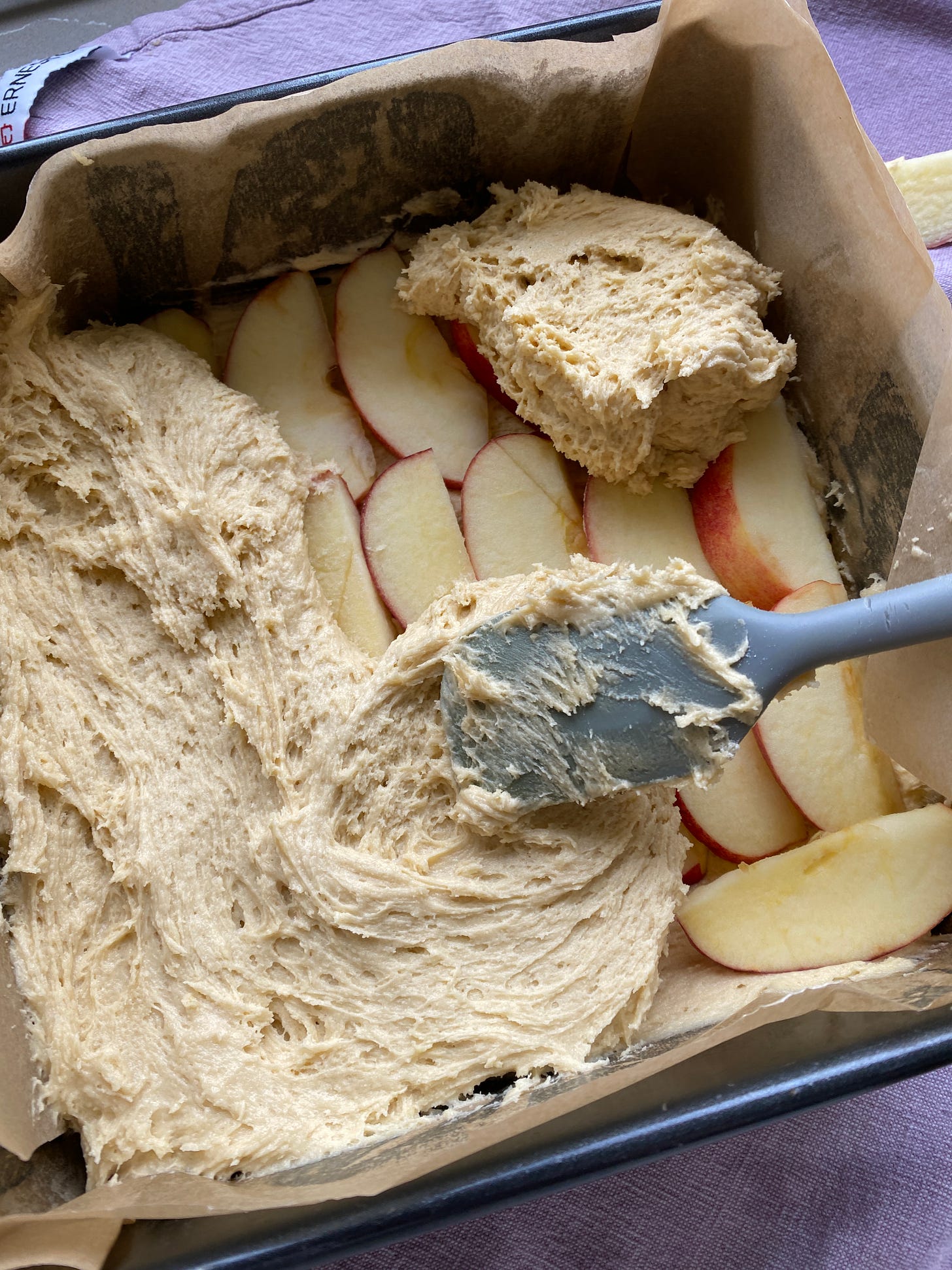 Repeat the process with the remaining cake mixture and apple slices. Then sprinkle demerara sugar over the top layer of apples.