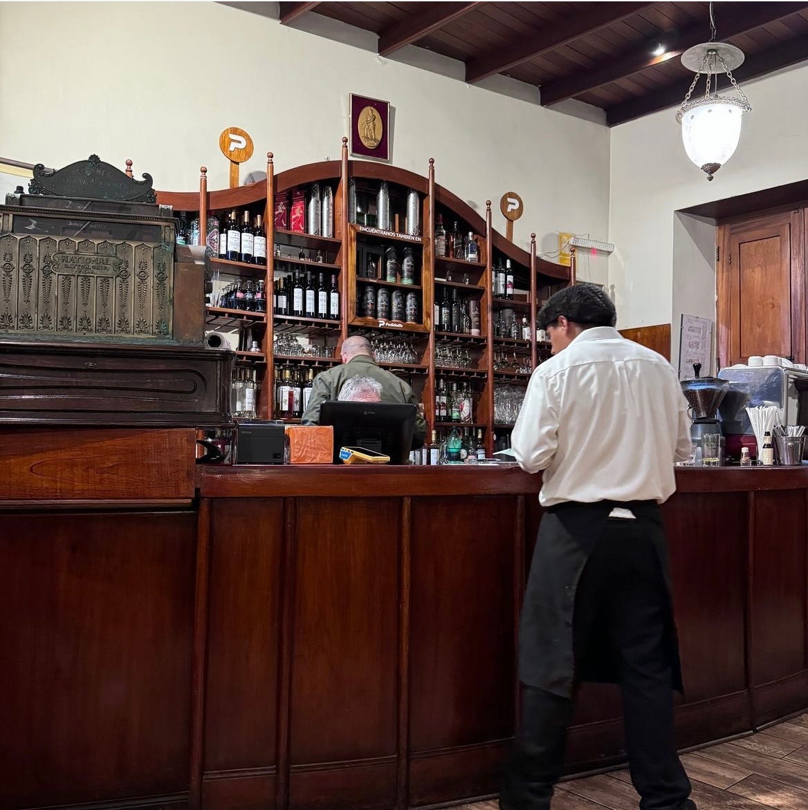 Server standing next to a dark wood bar at El Bolivariano