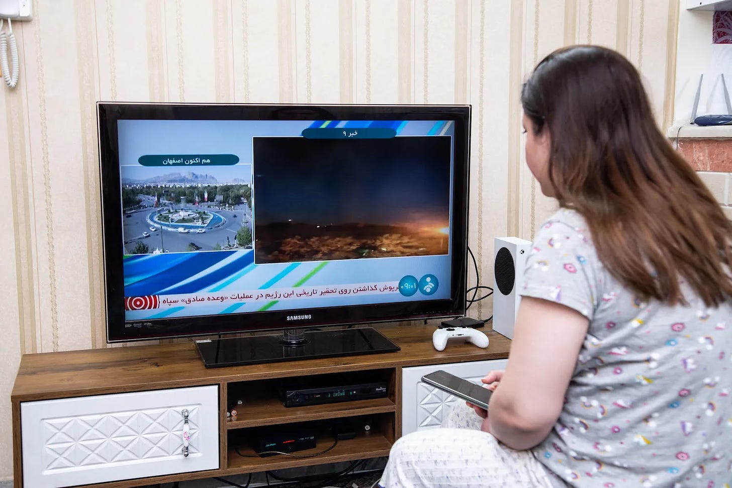 A woman watches an Iranian news TV channel covering an “explosion” near Isfahan, Iran.