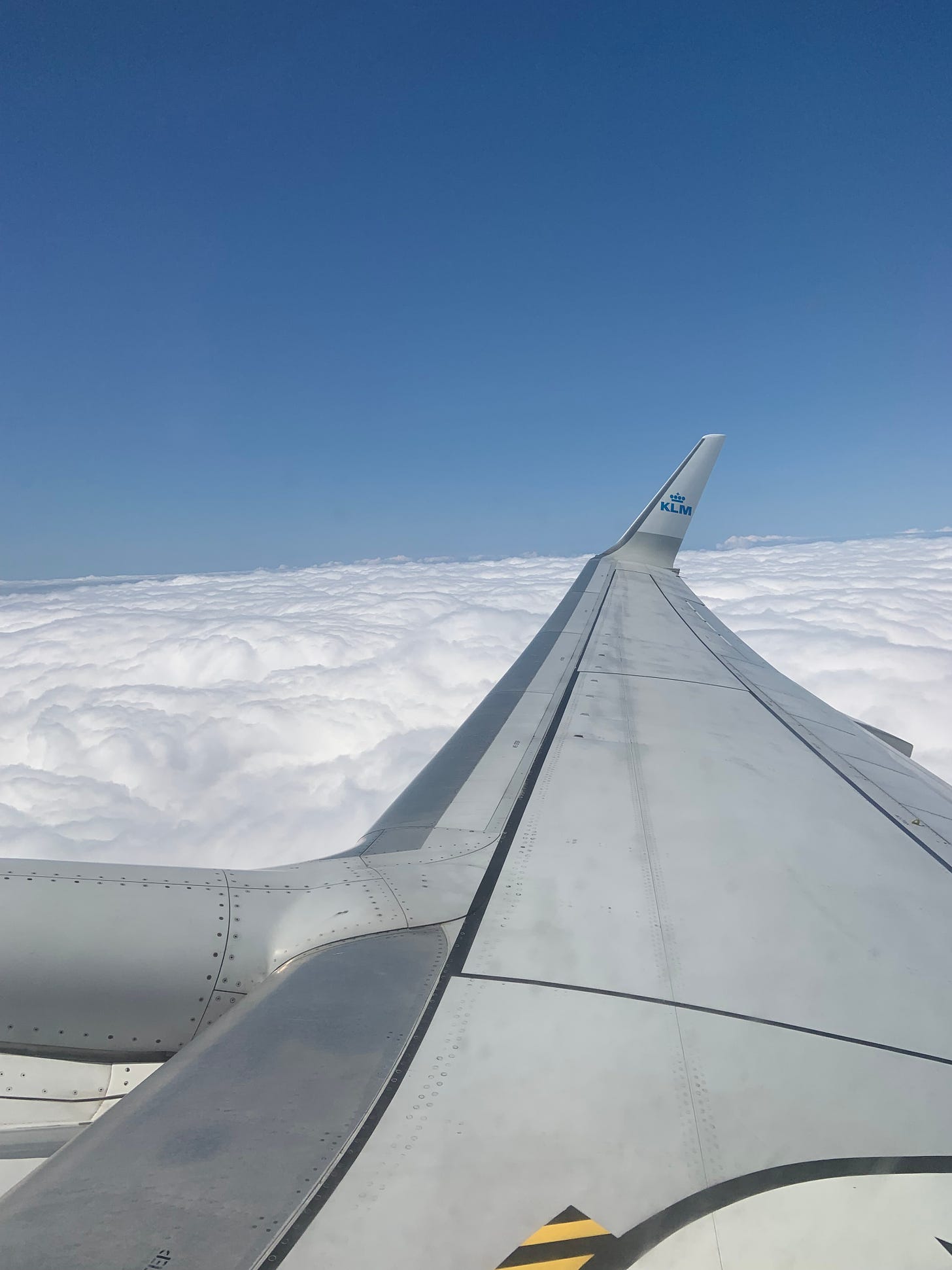 A photo of a KLM airplane wing above the clouds