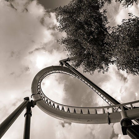 Black and white photo of part of a rollercoaster and trees.