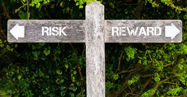 A wooden sign labeled "Risk" and "Reward" with two arrows pointing in opposite directions.