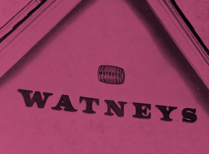 A cut plastic sign for Watneys on the side of a pub