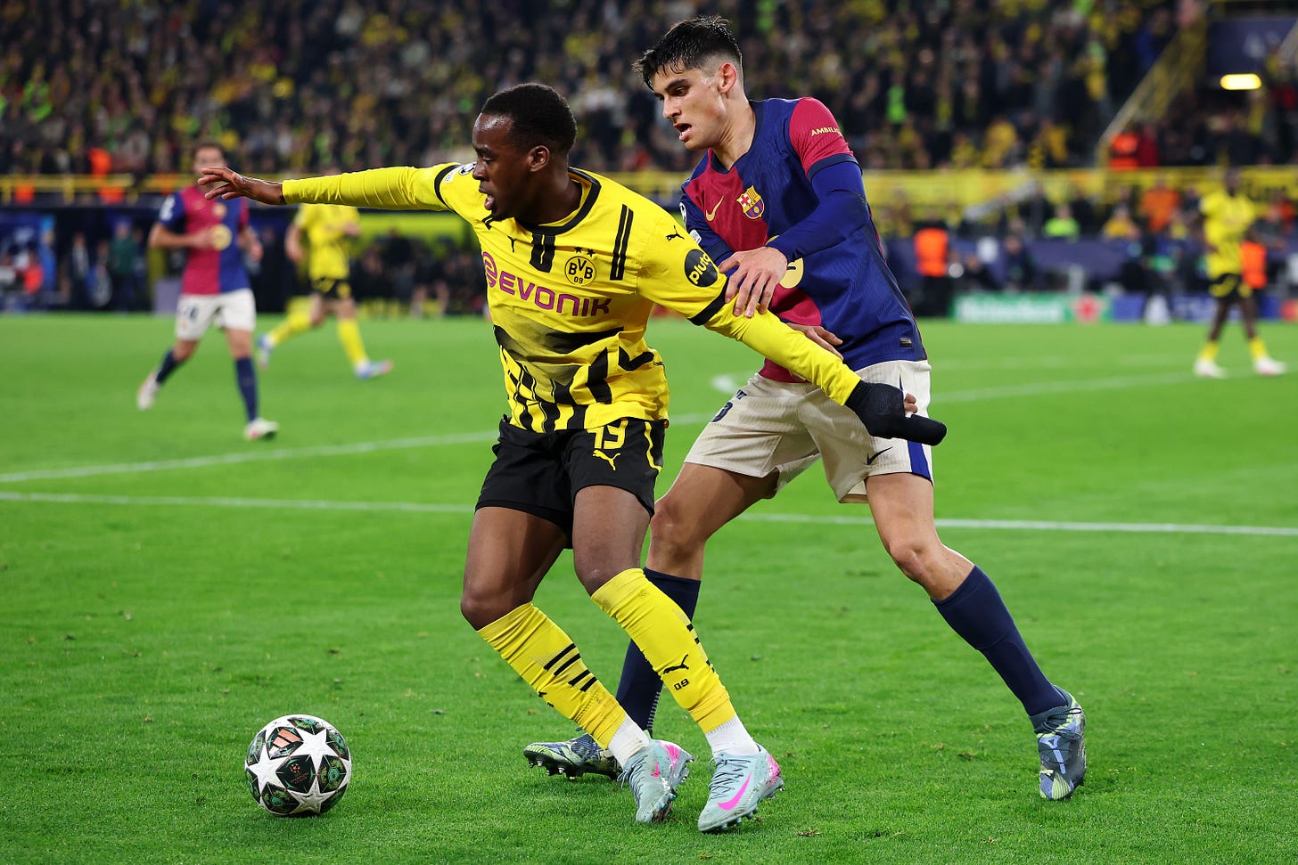 Jamie Gittens holds off Barcelona's Gerard Martin from getting the ball.