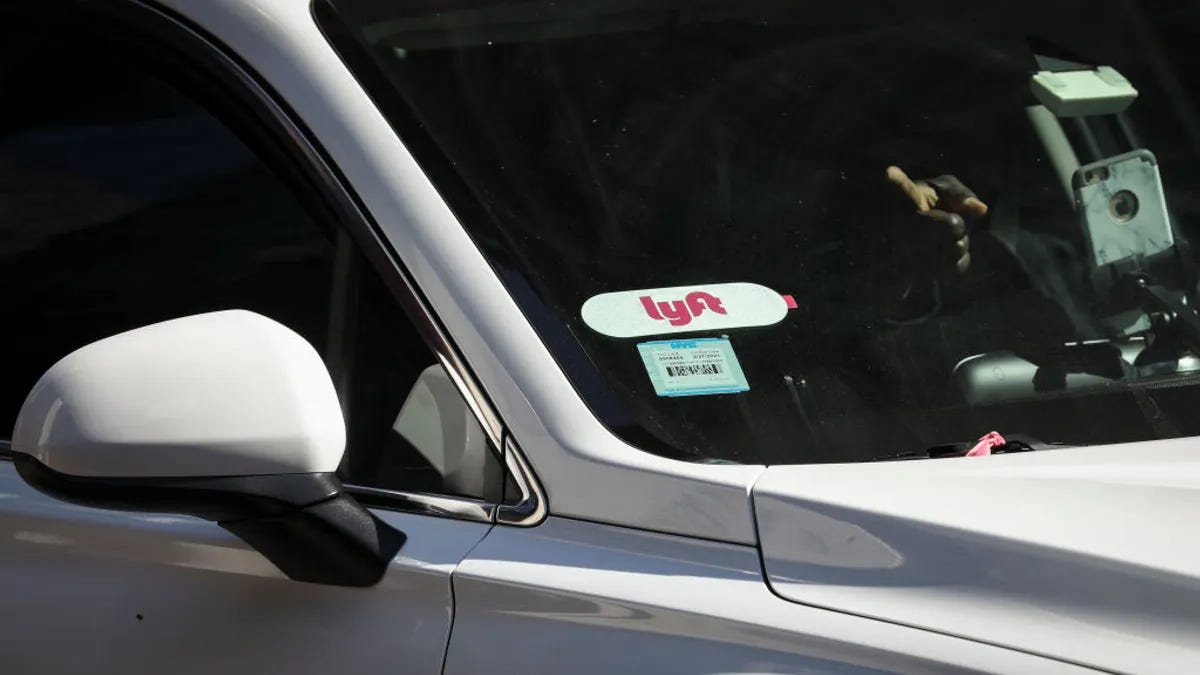A Lyft logo is displayed on a vehicle driving through Times Square.
