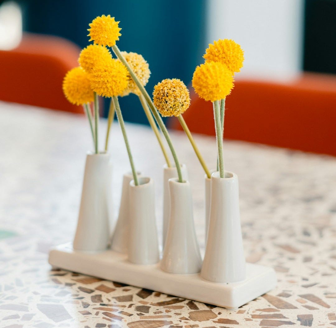 three white vases with yellow flowers in them