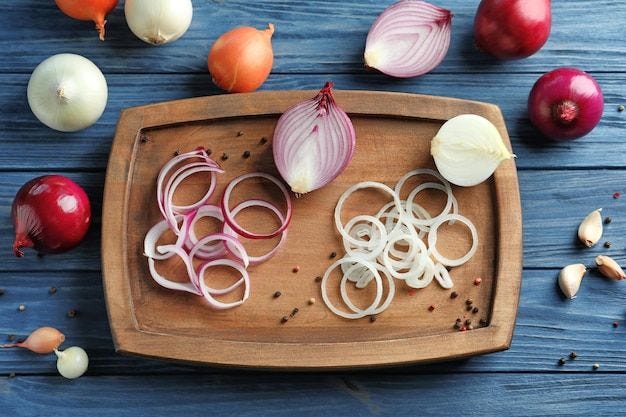 Photo composition with different onions on wooden table