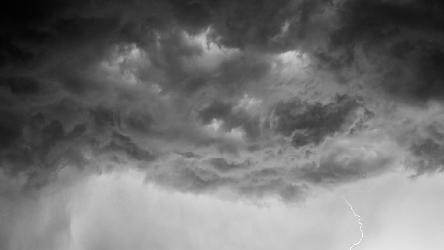 Photo of a dark and turbulent storm cloud with a bolt of lightning emerging underneath.