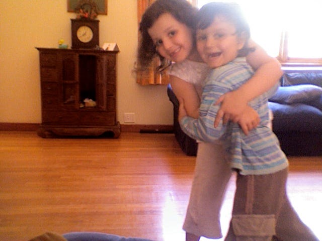 two young children hugging and peering at the camera with smiley faces