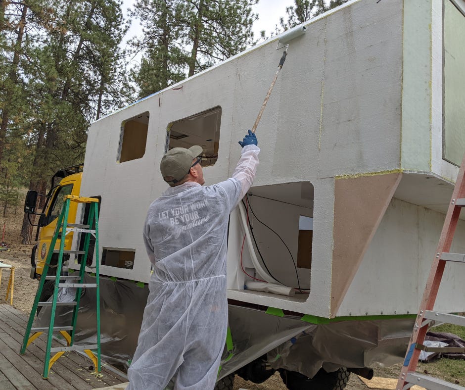 man in protective clothing rolling epoxy over sheets of fiberglass on the habitation box