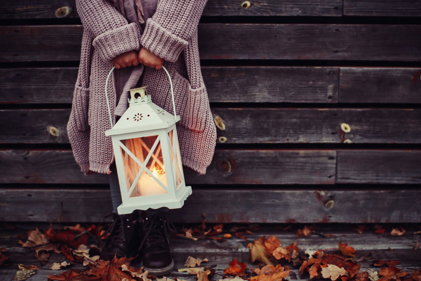 person in sweater holding a lantern