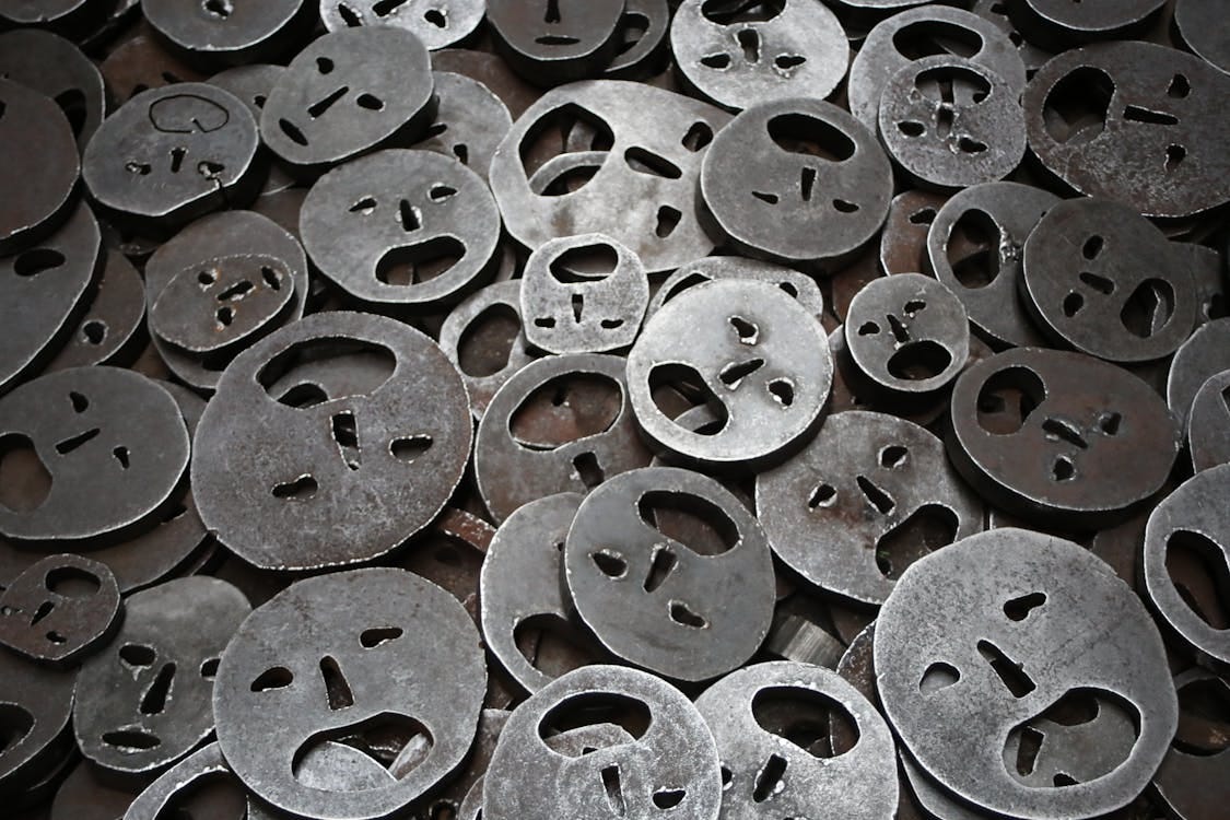 Free Close-up of metallic face cutouts symbolizing emotion in a Berlin art installation. Stock Photo