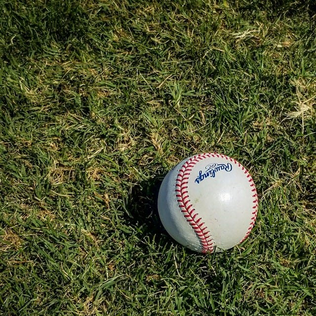 white and red baseball on green grass