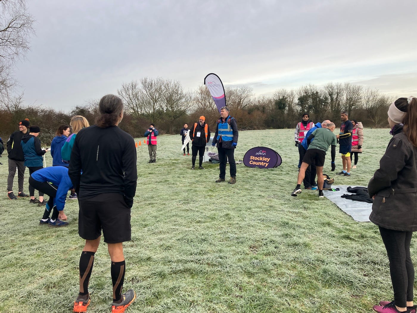 People gathered round the parkrun flag in the middle of a field
