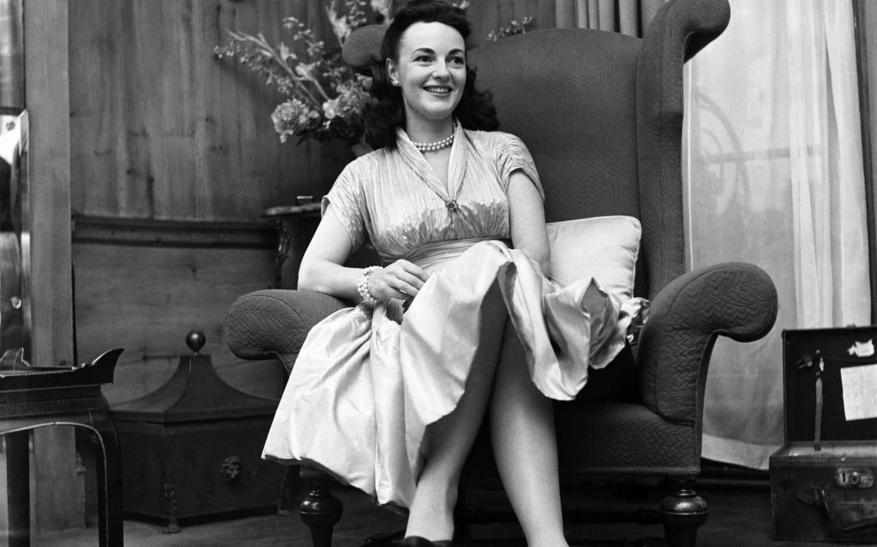 Author Kathleen Winsor sits in an armchair smiling 