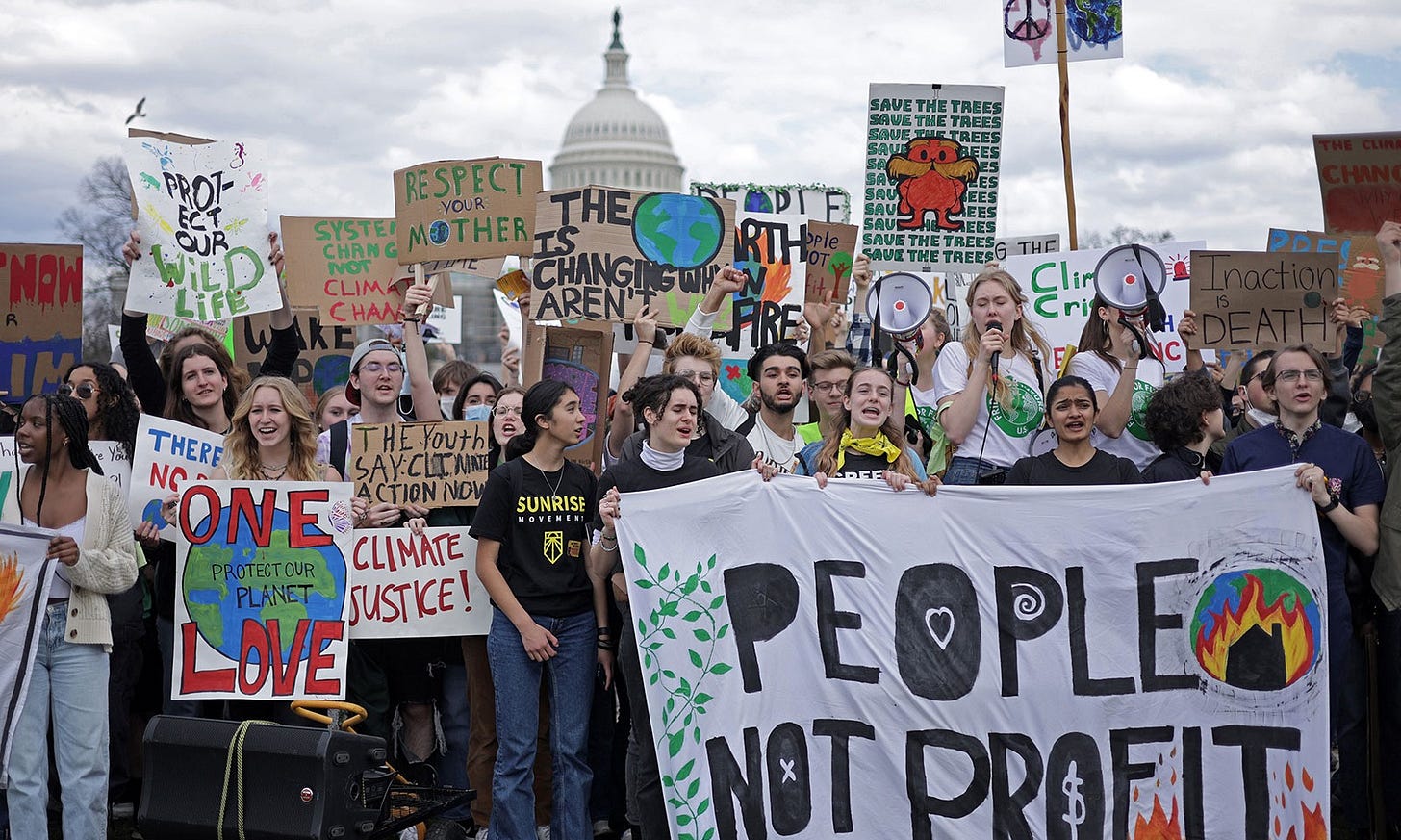 Large group of young people protesting climate change with USA capitol building in background Large group of young people protesting climate change with USA capitol building in background