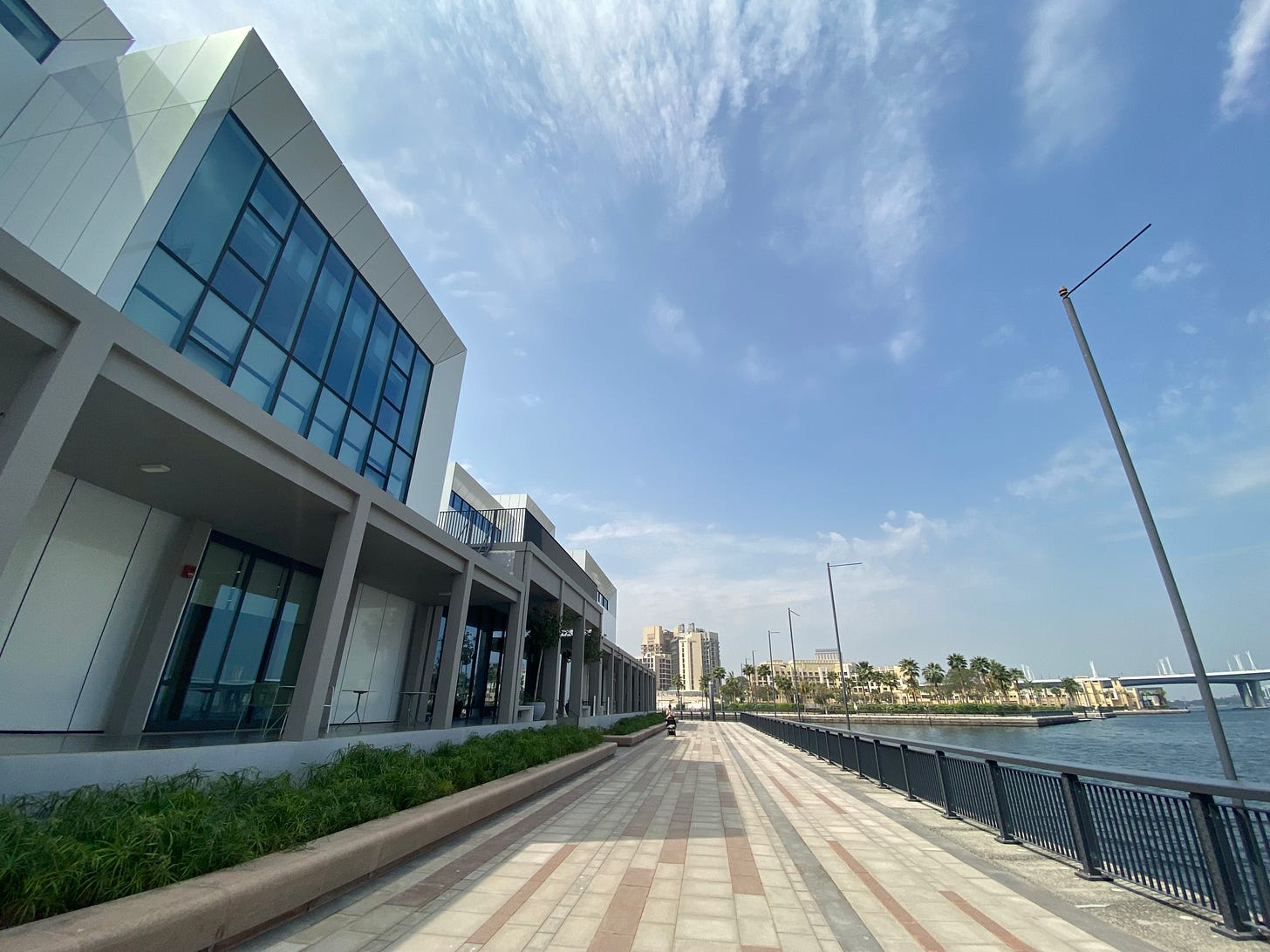 A mid-day photo of a walk path between Art Jameel and the Dubai Creek