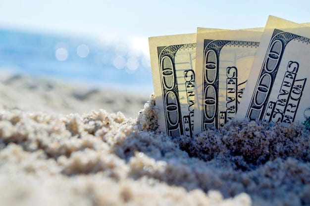 Três notas de dólar estão enterradas na areia na praia de areia perto do  mar em