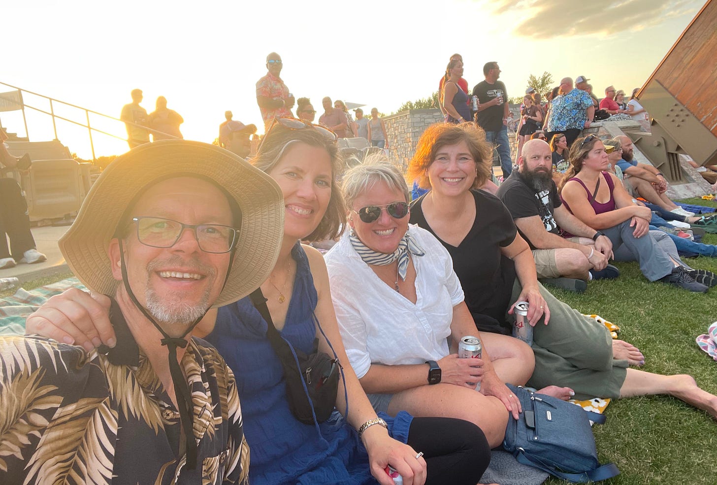 Four friends -- my husband, Jon, me and friends Rachel and Melissa -- sit with a crowd of other adults on a grassy hill as sunset approaches