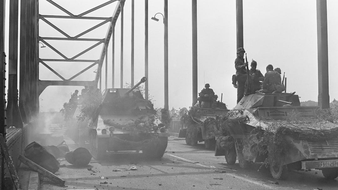 black and white photo of tanks crossing a bridge