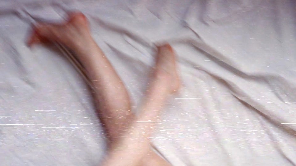 An image of legs on bedsheets