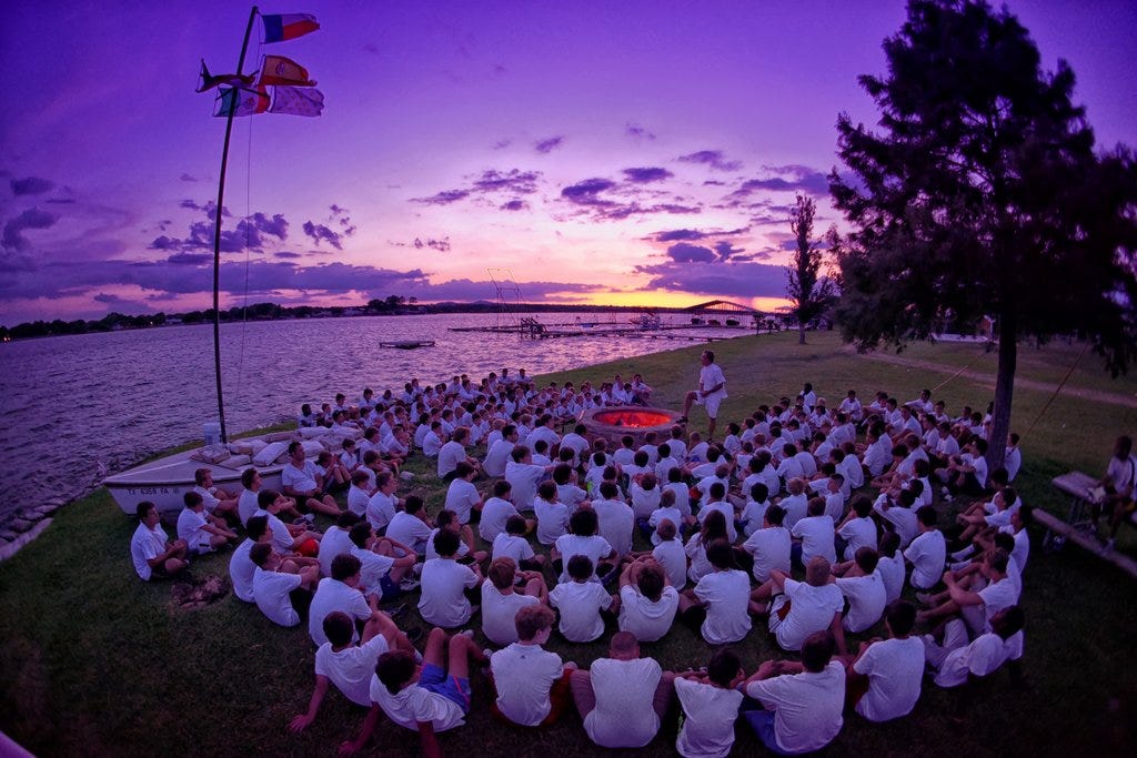 Campers sitting around a campfire in matching shirts