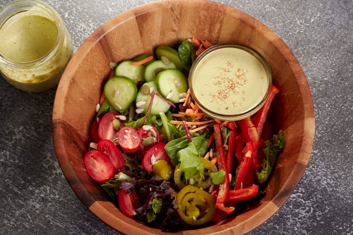 salad with a jar of vegan tahini salad dressing on the side