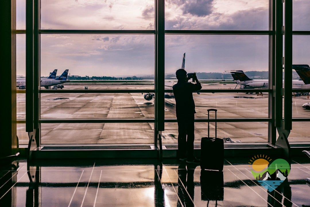 silhouette of person standing in front of glass while taking photo of plane