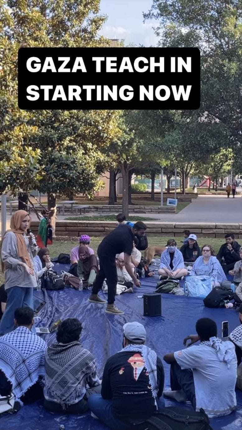 GAZA TEACH IN STARTING NOW. A woman in a hijab holds a microphone and stands with a ring of people, some wearing keffiyehs, on a tarp in front of her.