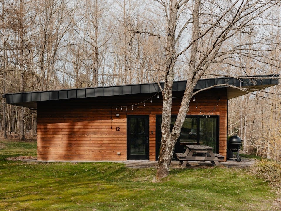 a small cabin in the woods with a picnic table