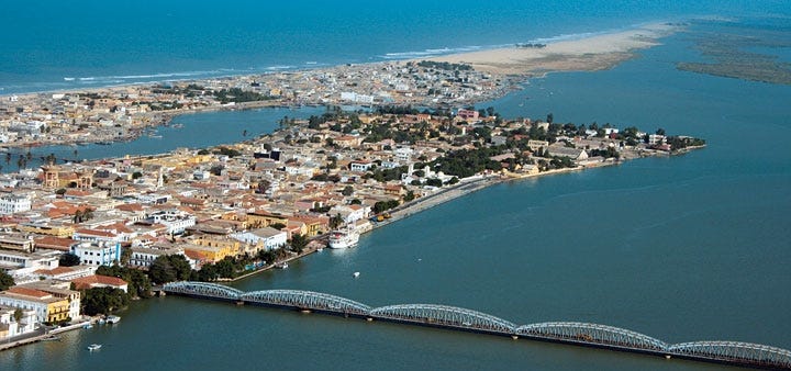 View of St. Louis, Senegal from the air. The center city (where no building is taller than 5 stories) is on a small island in the Senegal river, reached by a cantilever bridge.