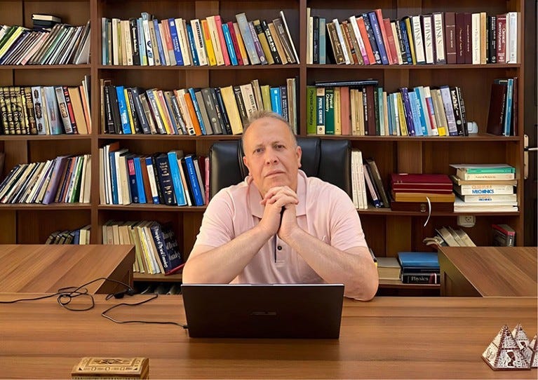Imad Barghouthi at a desk in front of bookshelves. Imad Barghouthi at a desk in front of bookshelves.
