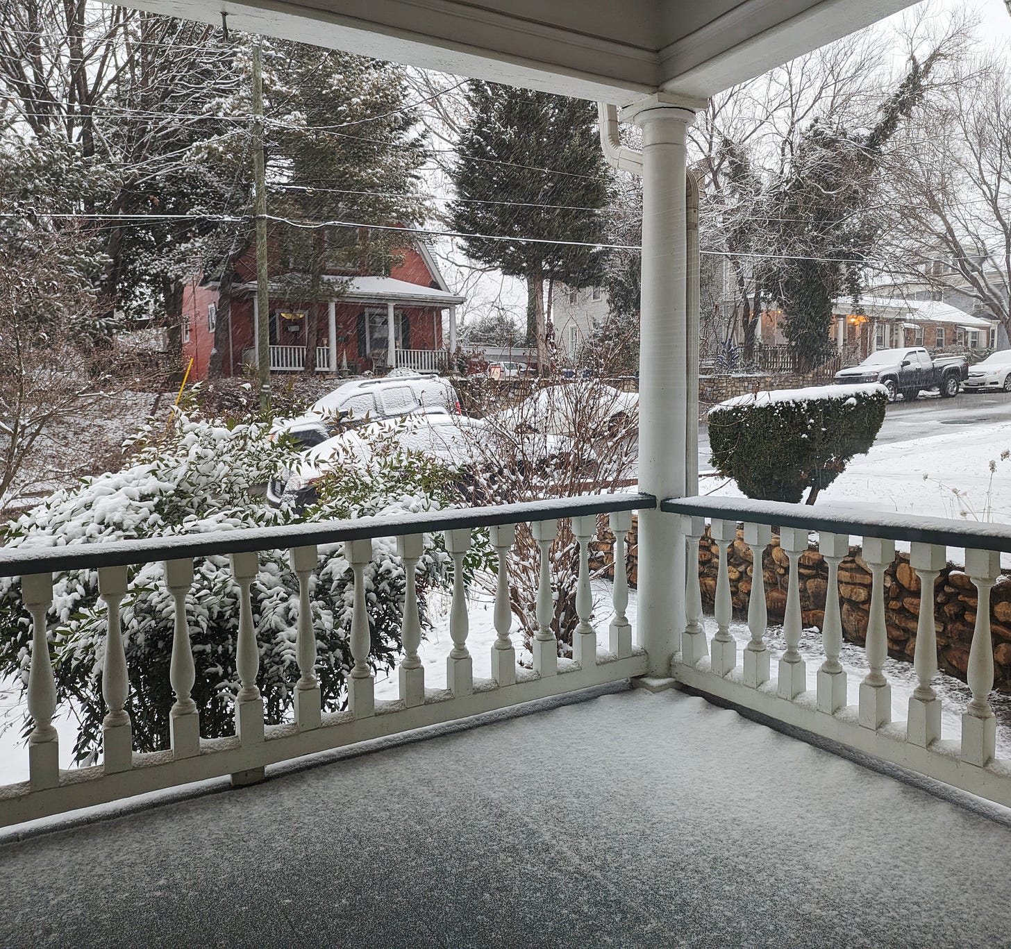 A snowy street, framed by a front porch railing.