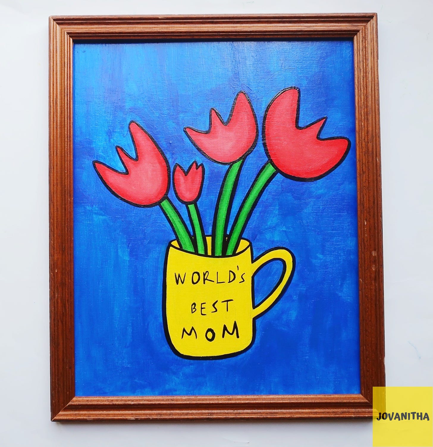 An oil painting of four red tulips in a yellow mug with the words world's best mom on a blue background in a thrifted frame
