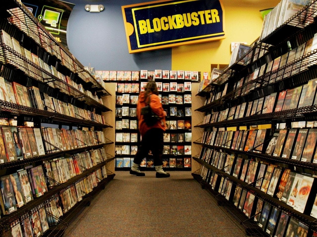 A woman browses video rentals in a Blockbuster, a business that was popular but collapsed due to not adapting to digital trends