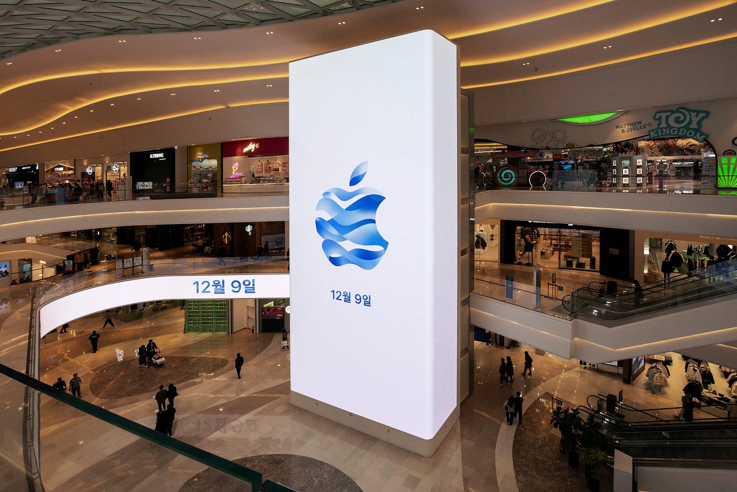 A digital billboard for Apple Hanam towers in the atrium of the mall. The billboard is near the store entrance.