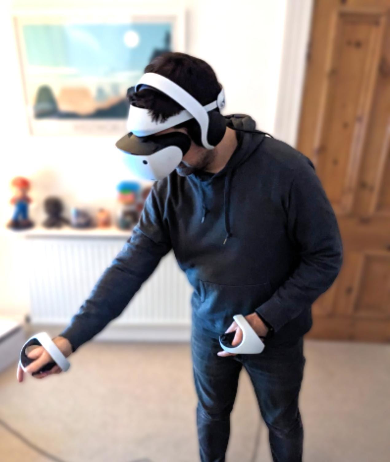 A man in a grey hoodie playing PSVR 2