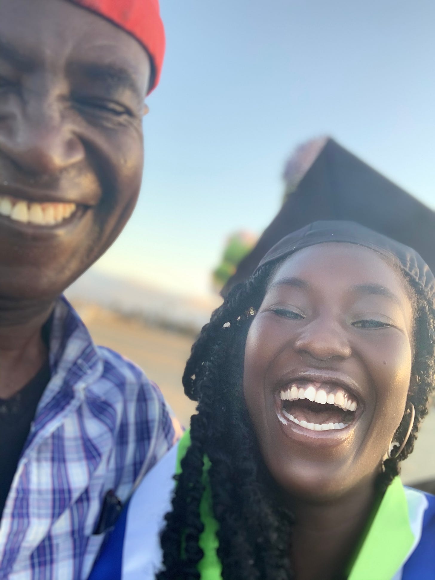 a picture of Ismatu next to their father in their graduation gear, both smiling