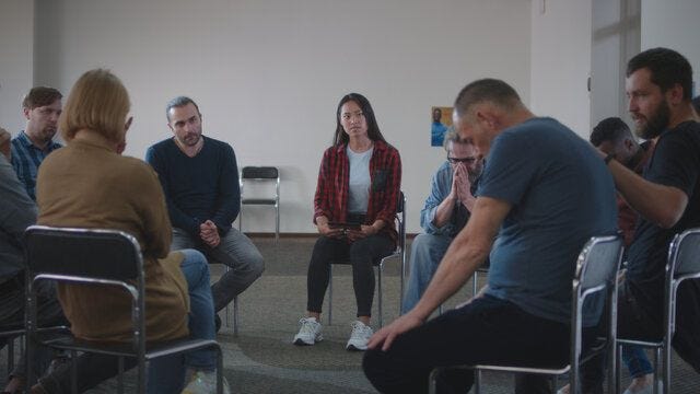 People supporting upset man during group meeting