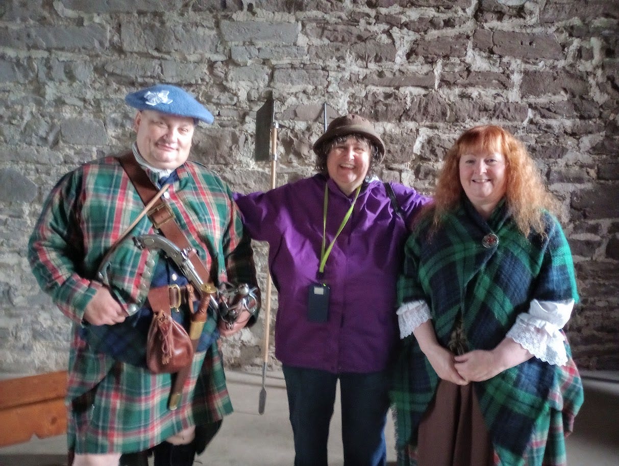 Man in tartan outfit with pistol and sword, woman in tartan dress