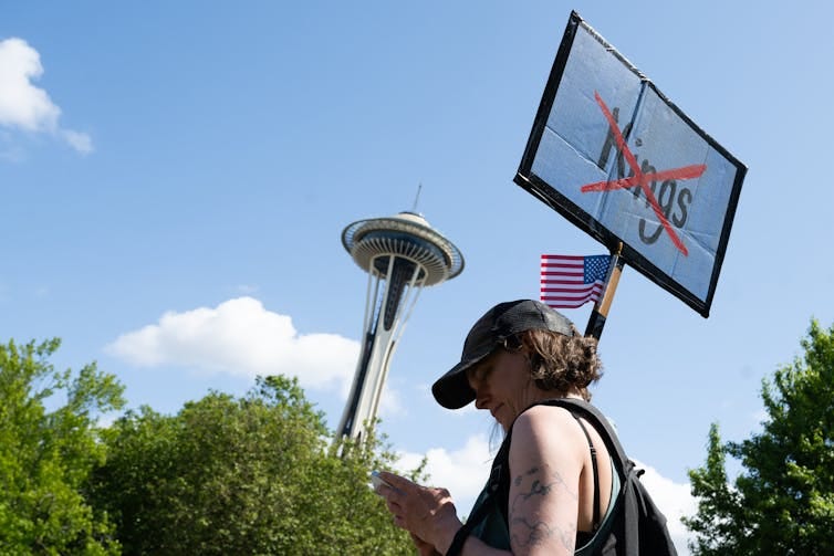 A person holds up a sign with the word kings crossed out A person holds up a sign with the word kings crossed out