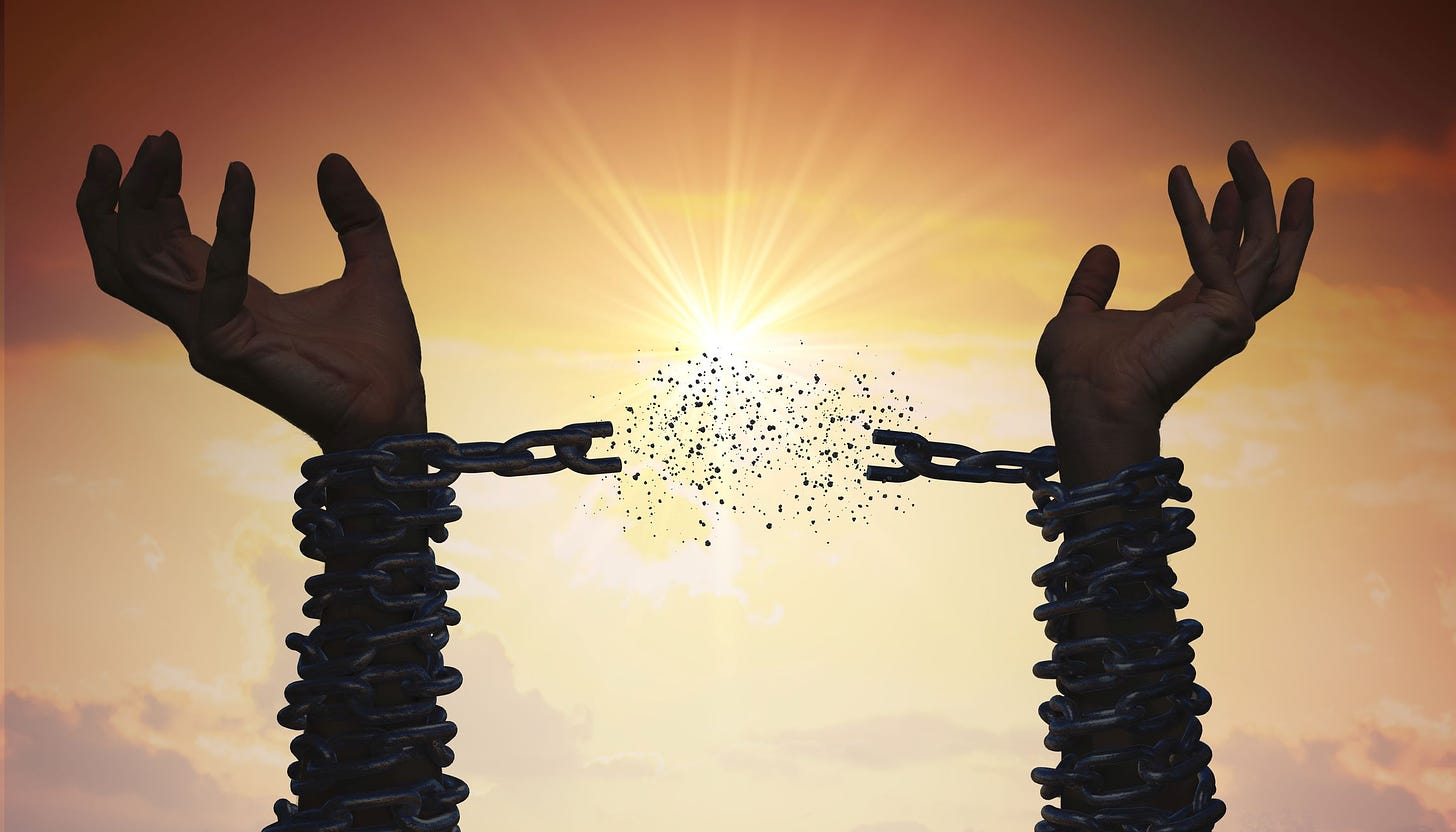 Silhouette of two hands in chains reaching toward the sky. The sun is shining in the background, and the chain that was holding them together is now broken.