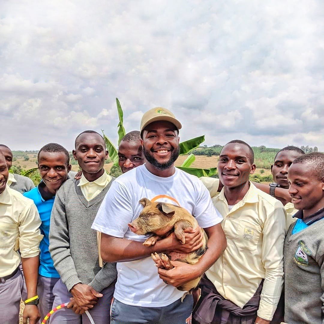 Pork Rhyne holding a piglet in Uganda on his mission trip