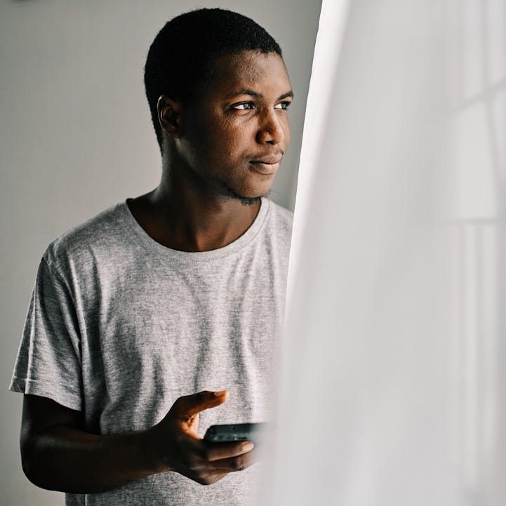 man in gray crew neck shirt standing beside white curtain