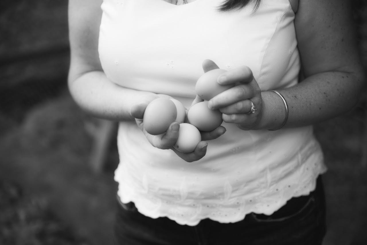 person in a white shirt holding 5 eggs