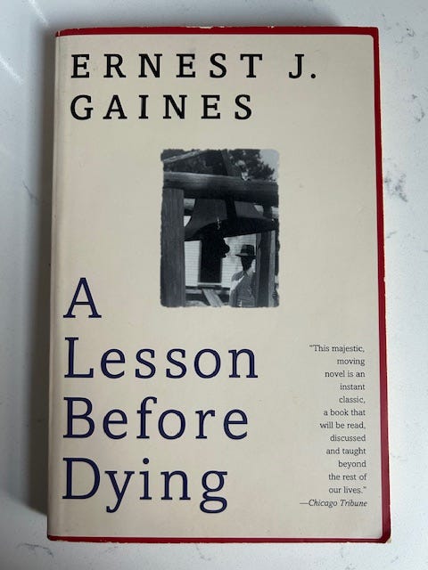 A tan background with a red border and blue lettering that reads Ernest J. Gaines A Lesson Before Dying