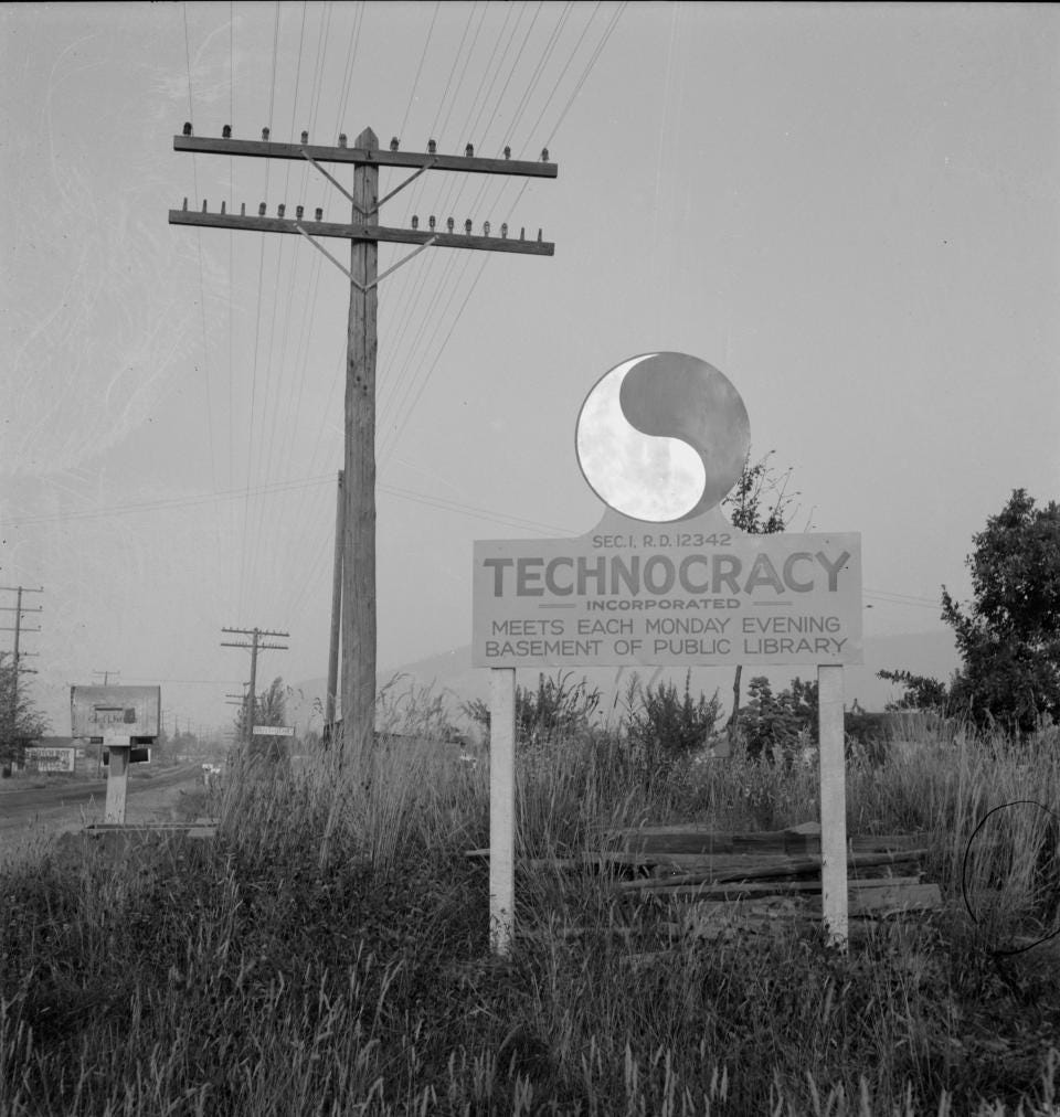 Black and white photo, Sign that reads 'Technocracy Incorporated - Meets Each Monday Evening - Basement of Public Library,' grassy field, power lines and empty road.