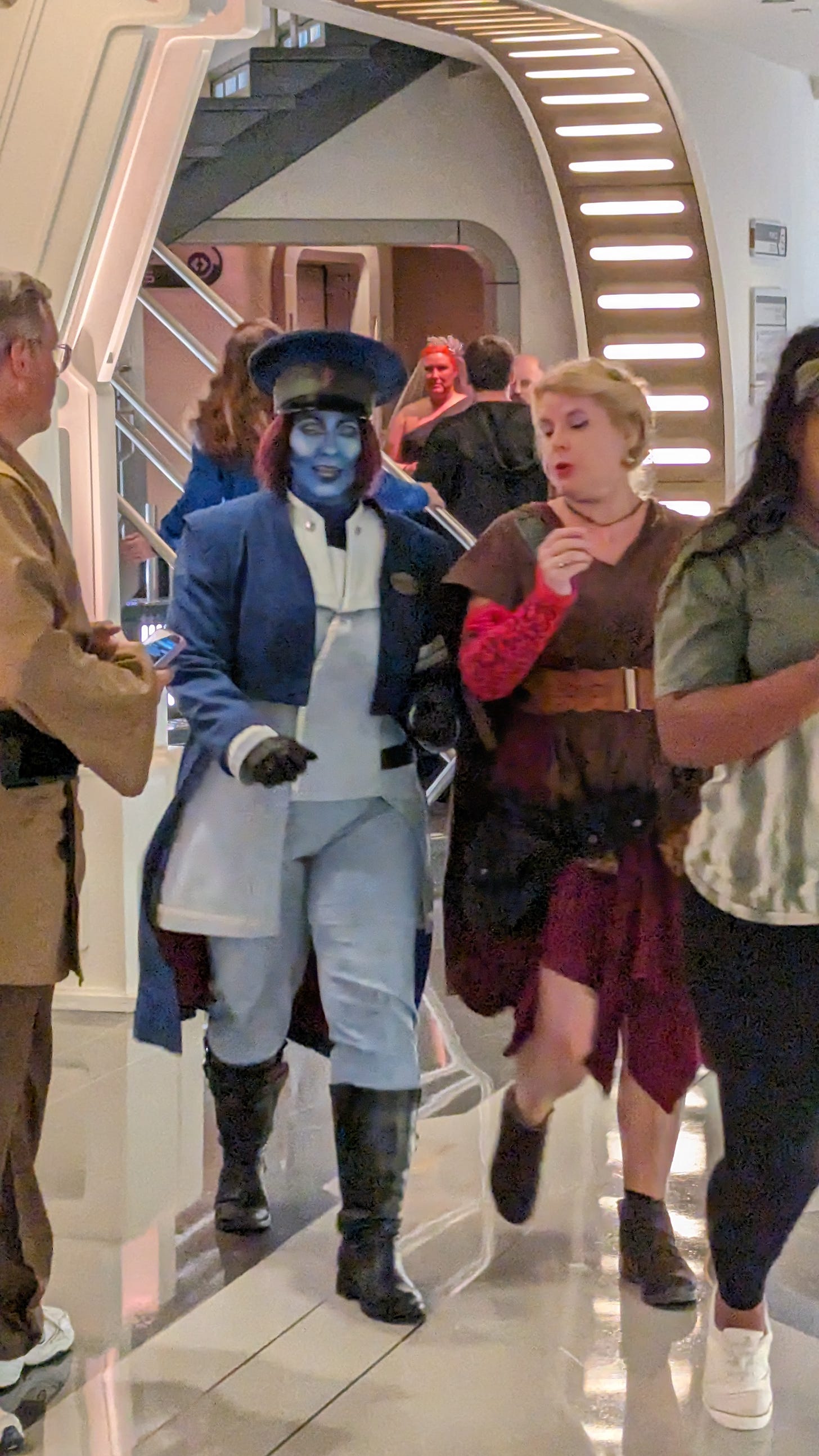 Cass and Captain Keevan crossing the Atrium amid a crowd