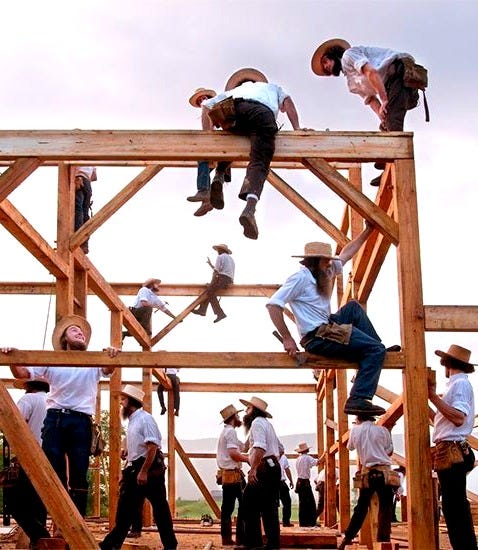 This may contain: men in white shirts and cowboy hats are on the roof of a house being built